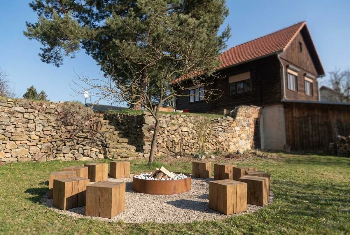 AI vizualizace zahrady na jaře — ohniště, dřevěné kostky, tráva